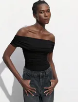 Body negro con escote bote drapeado y broches inferiores.