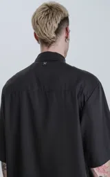 Camisa negra de manga corta con cuello clásico y cierre frontal con botones.