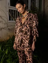 Conjunto estampado con hojas abstractas en tonos marrón y rosa, compuesto por una camisa de manga larga con puños anchos y un pantalón de corte recto.