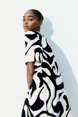 Vestido túnica a la rodilla de viscosa con estampado abstracto en blanco y negro. Tiene cuello mao, abertura en V, corte holgado, hombros caídos, mangas cortas, bajo recto y tajos laterales.