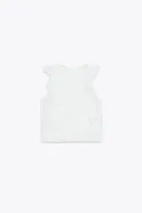 Blusa blanca semitransparente de cuello redondo y sin mangas, con volantes en los hombros y en el frente.