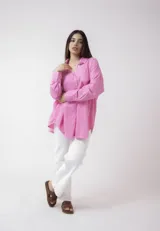 Camisa blanca de lino, de corte holgado, con cuello clásico, cierre frontal con botones, bolsillo en el pecho y mangas largas con puños abotonados.