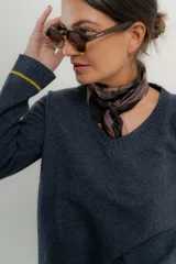 Sweater azul de punto con cuello en V y puños con detalle de rayas amarillas.