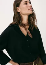 Camisa negra de corte holgado, con cuello clásico, cierre frontal con botones y mangas 3/4.