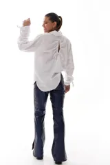 Camisa blanca de algodón con cuello clásico, mangas largas con puños fruncidos y cierre de botones al frente. Presenta frunces y lazo ajustable en la espalda.