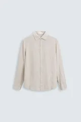 Camisa de hombre regular fit confeccionada en tejido de lino color crudo. Tiene cuello solapa, manga larga con puños abotonados y cierre frontal con botones.