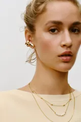 Pack de dos aros dorados: uno tipo earcuff con forma de espiral y otro con forma de C.