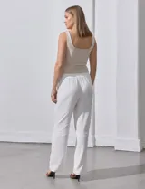 Pantalón de lino a rayas verticales color beige y blanco, con pretina ancha elastizada, lazo de ajuste y bolsillos inclinados.