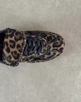 Zapatillas deportivas de cuero vacuno con estampado animal print de vaca en blanco y marrón.
