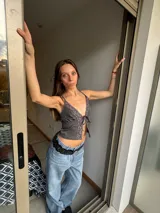 Top gris con breteles finos, escote en V con terminación de encaje y lazo ajustable en el centro.