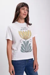 Remera blanca de algodón con estampado de una flor amarilla y hojas verdes, con la frase "The world in bloom".