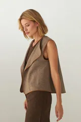 Chaleco marrón con solapas amplias y terminaciones envivadas. Diseño reversible y sin mangas.