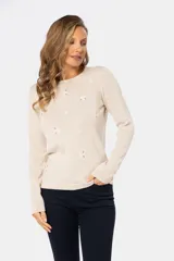 Buzo color beige de tejido de punto con bordado de pequeñas flores blancas.
