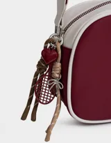 Bandolera de cuerina azul marino y beige con correa regulable azul y charm lateral decorativo. Tiene cierre superior y tag frontal con logo "The Brunch Club".