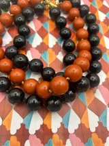 Collar de cuentas redondas de color negro y naranja alternadas.