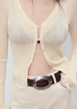 Cardigan de punto fino color crema, con escote en V y cierre frontal de botones. Presenta ribetes en contraste en los puños y un tejido semitransparente.