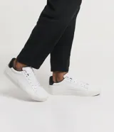 Championes casuales de cuero sintético color blanco con detalle de talón en cuero sintético negro.