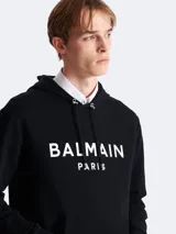 Buzo hoodie negro de algodón con logo Balmain Paris estampado en blanco en el frente.