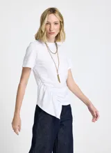 Remera blanca de punto con cuello redondo, mangas cortas, frunce lateral y bajo asimétrico.