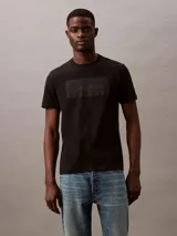 Remera negra de algodón con cuello redondo y mangas cortas. Presenta un logo de Calvin Klein en relieve en el pecho.
