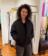 Chaqueta negra capitoneada con botones dorados.