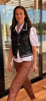 Chaleco de jean negro con apliques de caracoles cosidos a mano en los bordes.