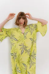 Vestido largo color amarillo con estampado de hojas verdes y grises, escote en V y mangas 3/4 amplias.