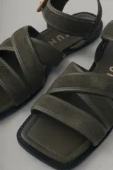 Sandalia plana de cuero color verde militar, con tiras cruzadas en el empeine y una tira ajustable con hebilla metálica dorada en el tobillo.