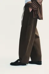 Pantalón cargo negro de corte amplio con cintura ajustable con cordón, bolsillos laterales y bolsillos tipo parche en las piernas.