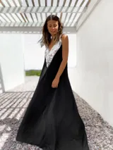 Vestido largo negro con escote en V y breteles finos. Presenta un aplique triangular de lentejuelas plateadas en la parte superior.