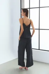 Conjunto de pijama color blanco hueso, compuesto por un top de breteles finos regulables con detalle de puntilla en el escote, y un pantalón de corte recto con cintura elástica y bolsillos laterales.