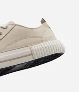 Championes bajos de lona color beige, con puntera redonda, cierre con cordones y suela de goma blanca con detalle de línea en relieve.
