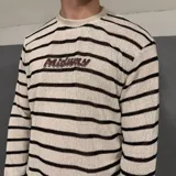 Sweater tejido a rayas horizontales grises y blancas con logo amarillo bordado en el pecho.