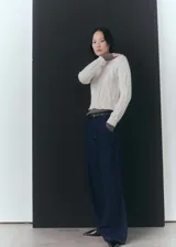 Sweater color crema de punto trenzado, con cuello Perkins y mangas largas con puños elásticos.