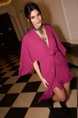 Vestido corto fucsia tipo kimono con mangas abiertas y tiras ajustables en la cintura.