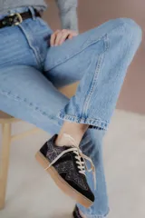 Championes acordonados color beige y dorado con suela marrón.