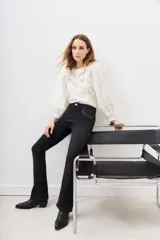 Pantalón de jean negro de corte flare con detalle de tachas metálicas en los bolsillos delanteros.