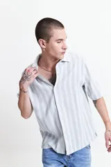 Camisa celeste a rayas verticales blancas, de manga corta y corte oversize.
