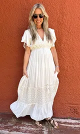 Vestido largo color crudo, de seda con bordados en el mismo tono, escote en V, mangas cortas con volados y corte imperio.