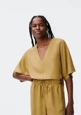 Blusa color ocre de corte holgado, con escote en V y mangas cortas amplias.
