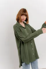 Camisa verde militar con estampado de lunares blancos, de corte oversize, con cuello camisero, cierre frontal con botones y bolsillo en el pecho.