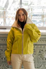 Chaqueta bomber de cuero color marrón, con cuello de piel sintética roja, cierre frontal con cremallera y bolsillos laterales.