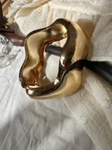 Brazalete rígido plateado con diseño irregular y anillo a juego.