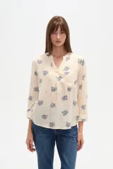 Blusa de manga tres cuartos color crema con estampado floral en azul. Presenta cuello mao con abertura en V y un bolsillo de parche en el pecho.