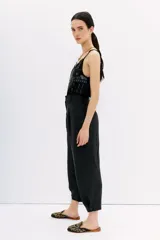 Pantalón sastrero negro con ajuste en el tobillo, tiro alto, bolsillos delanteros y traseros, pinzas en el frente, confeccionado en cupro y viscosa.