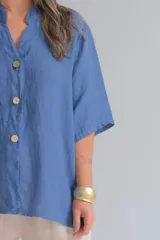 Camisa azul jean de lino, con cuello mao, manga corta y cierre frontal con botones.