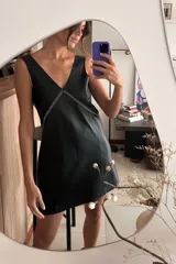 Vestido corto negro de cuero ovino, corte holgado, escote en V y bordado a mano en el frente.