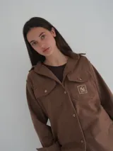 Camisa gris de lana con corte clásico, cuello camisero, cierre frontal con botones de cuerno y dos bolsillos de parche en el pecho.