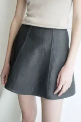 Minifalda negra de cuero con corte en A y costuras verticales decorativas.