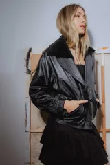 Campera bomber negra de cuero con cuello de piel sintética, forro interior y detalles de pasamanería en cuero marrón gastado.